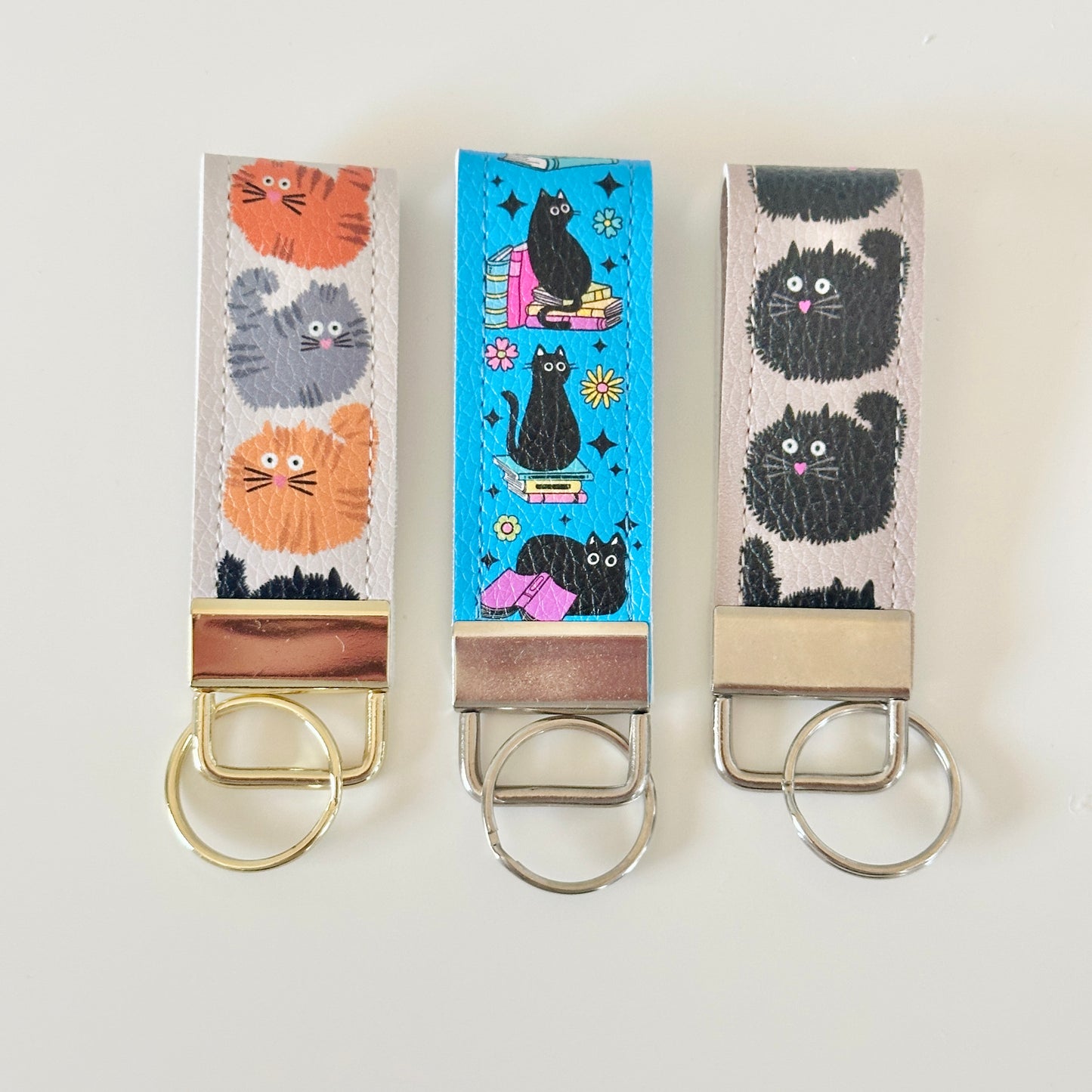 Three keychains with cat designs on a white background