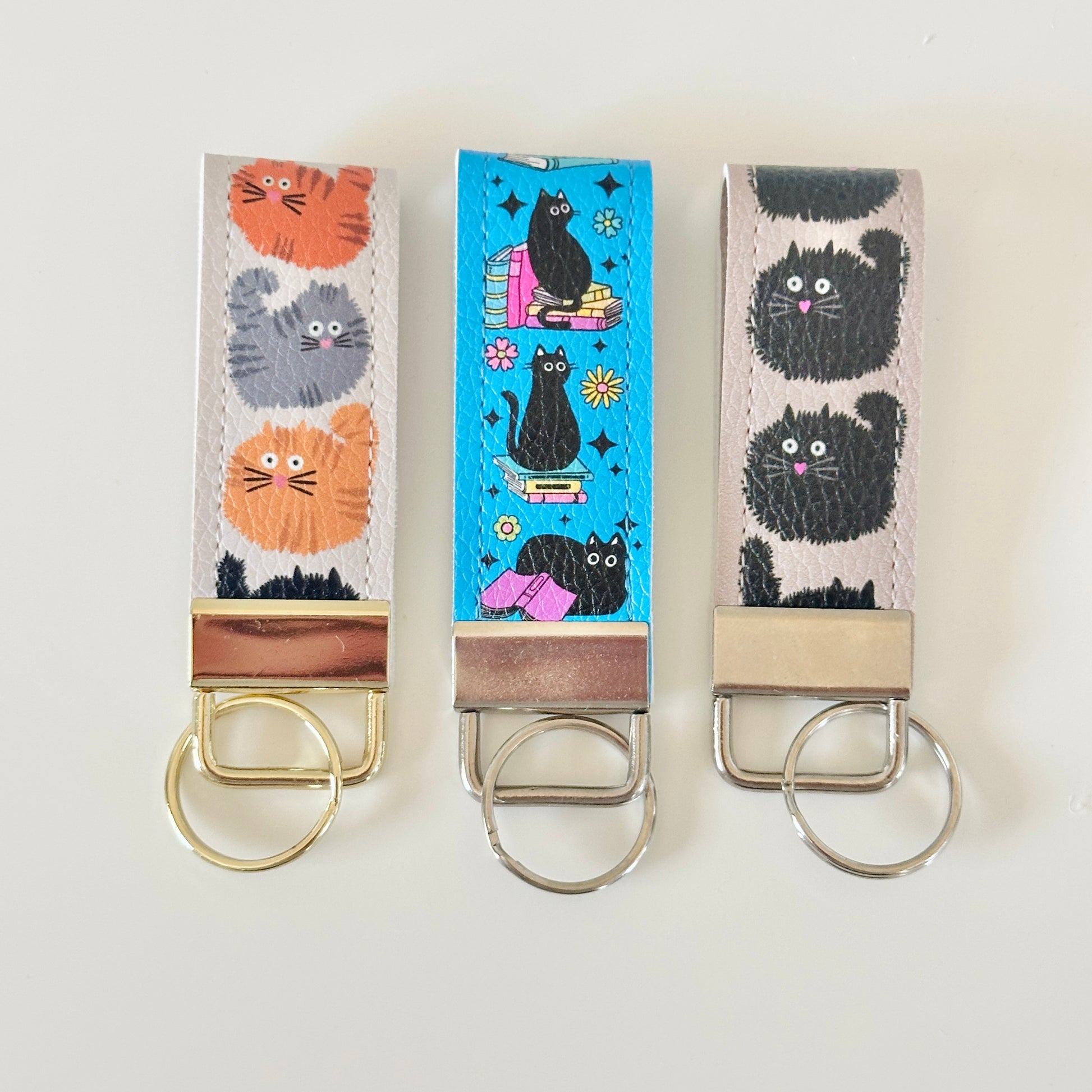 Three keychains with cat designs on a white background