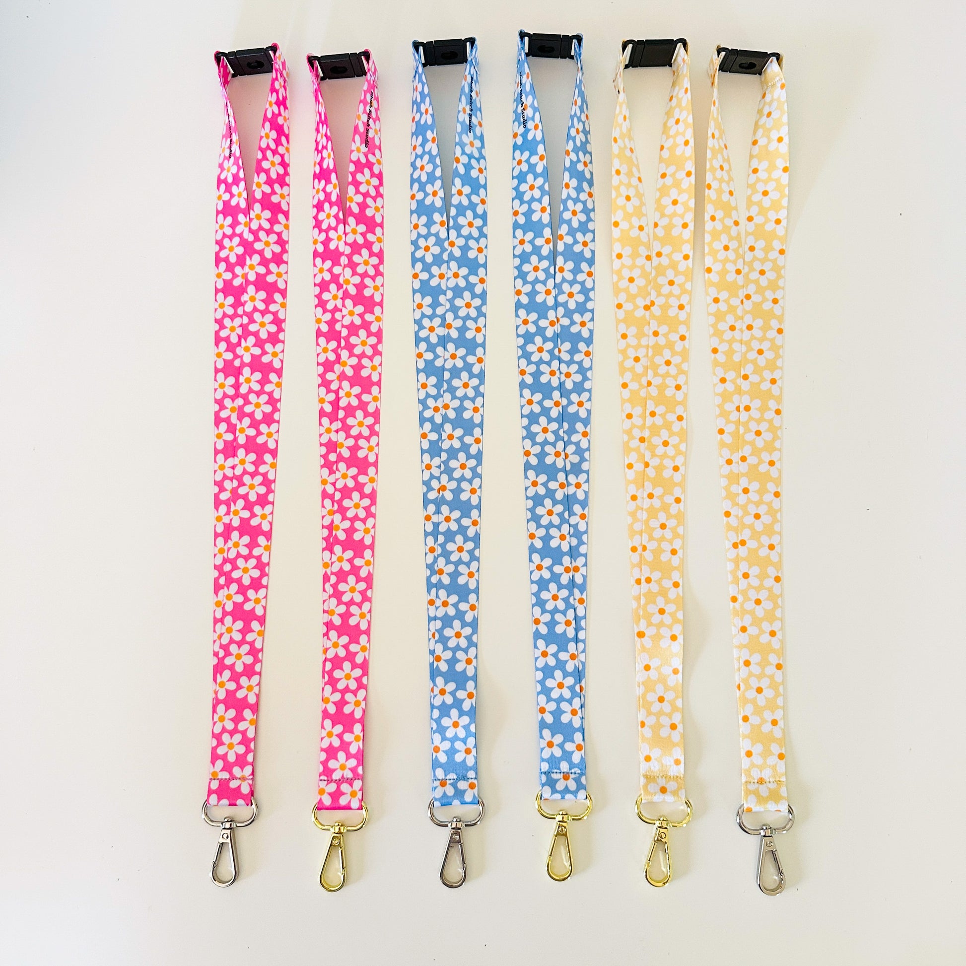 Four floral-patterned lanyards in pink, blue, and yellow on a white background