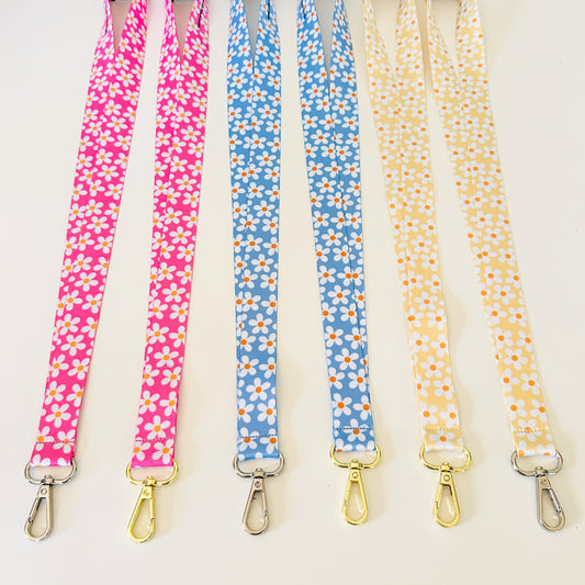 Four  daisy floral lanyards in pink, blue, and yellow on a white background