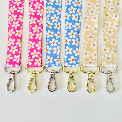 Four  daisy floral lanyards in pink, blue, and yellow on a white background