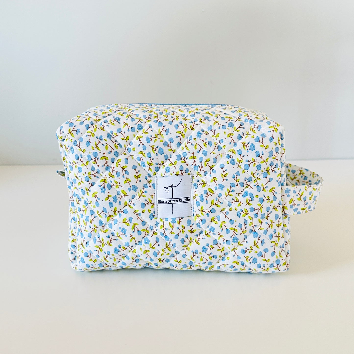 Floral-patterned pouch with a visible brand label on a light background
