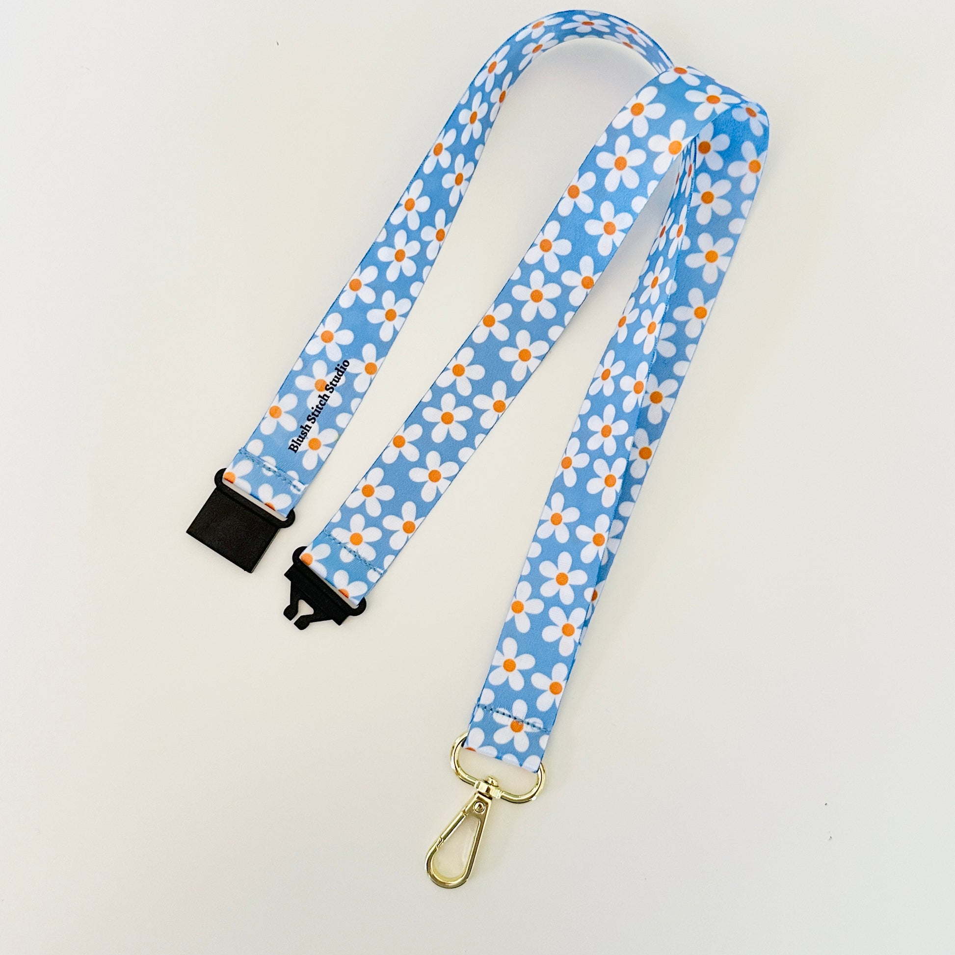 blue daisy lanyard with a gold clasp 