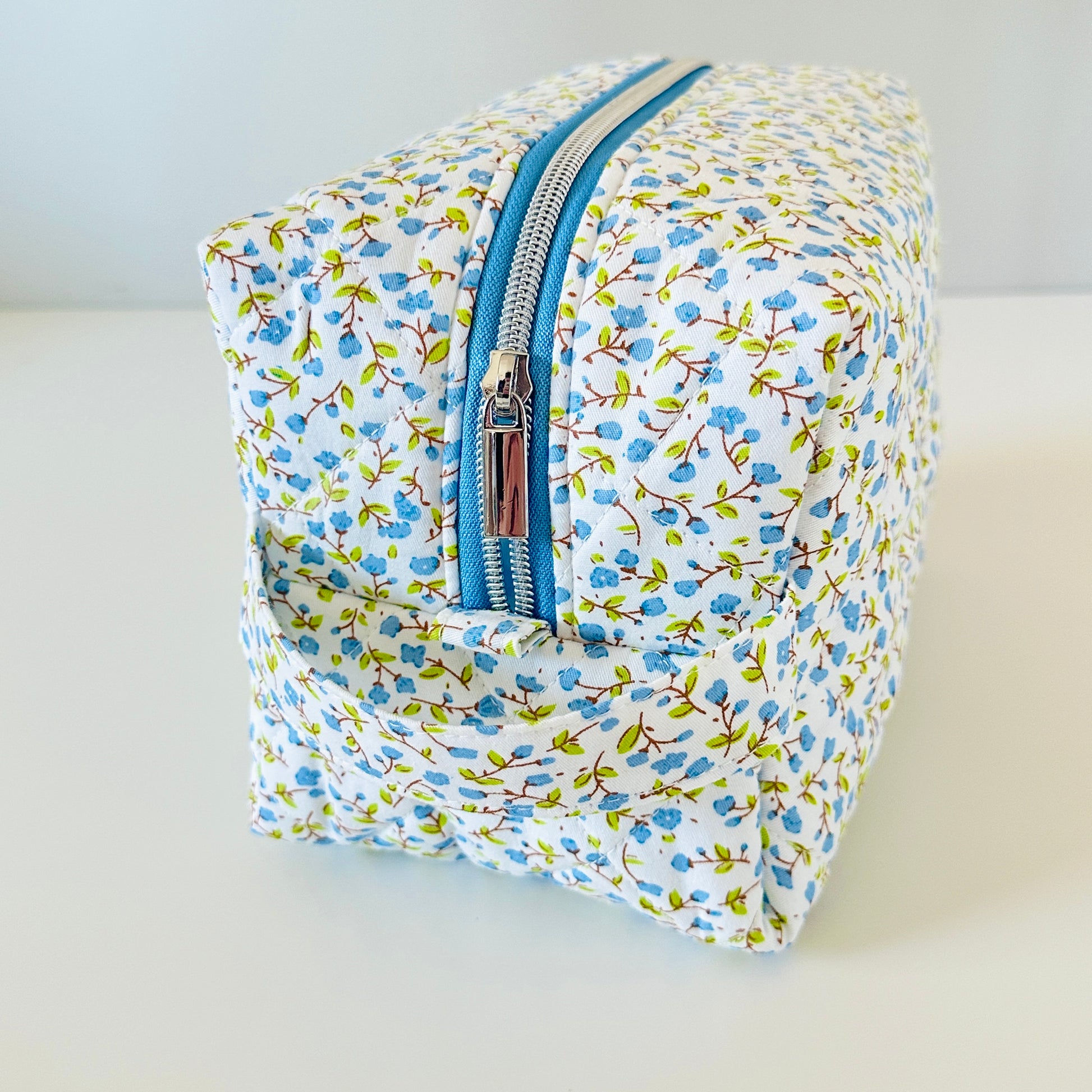 Floral-patterned toiletry bag with a blue zipper on a light background