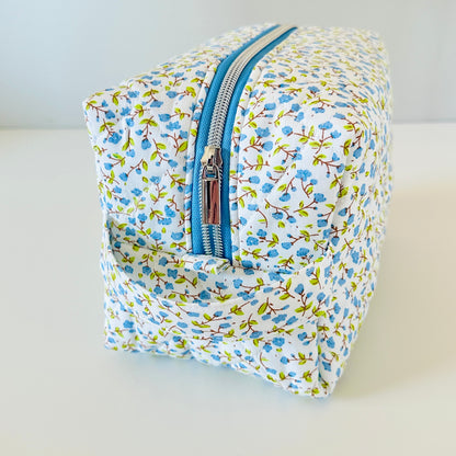 Floral-patterned toiletry bag with a blue zipper on a light background