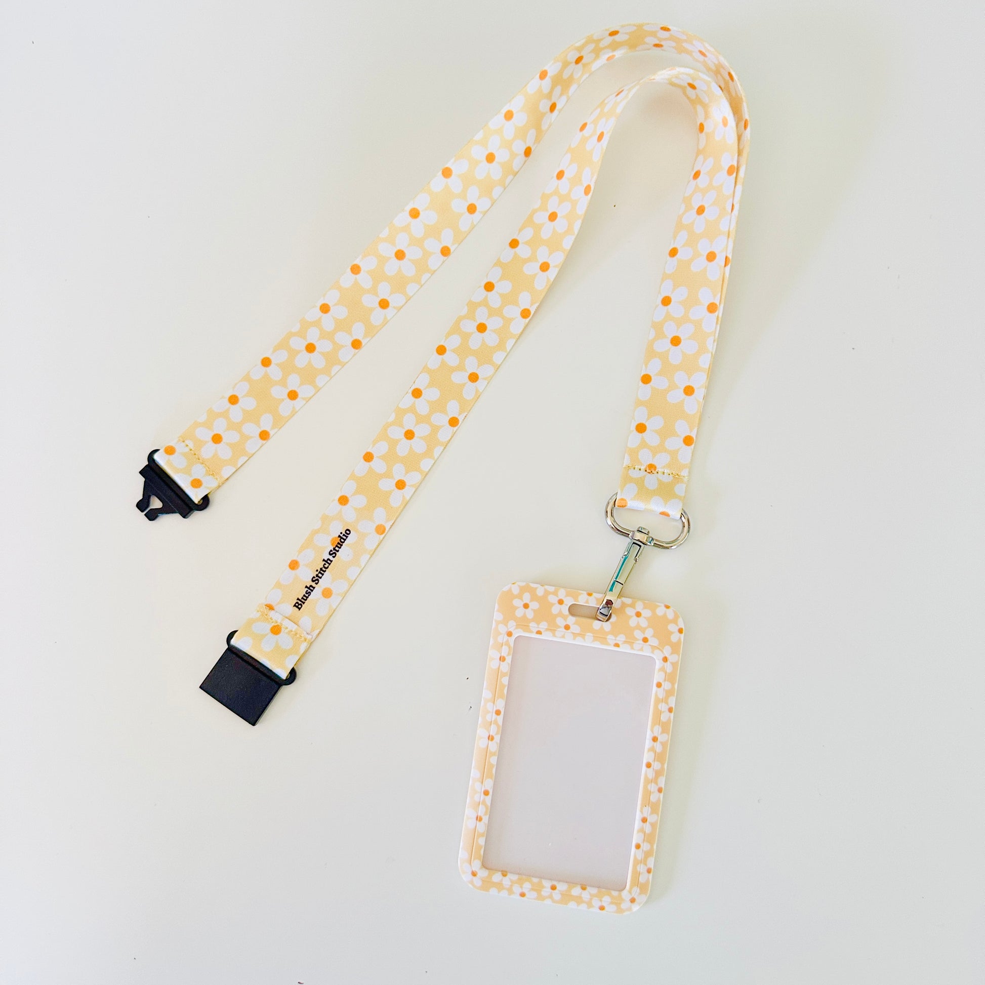 yellow daisy floral lanyard with a matching ID holder on a light gray background