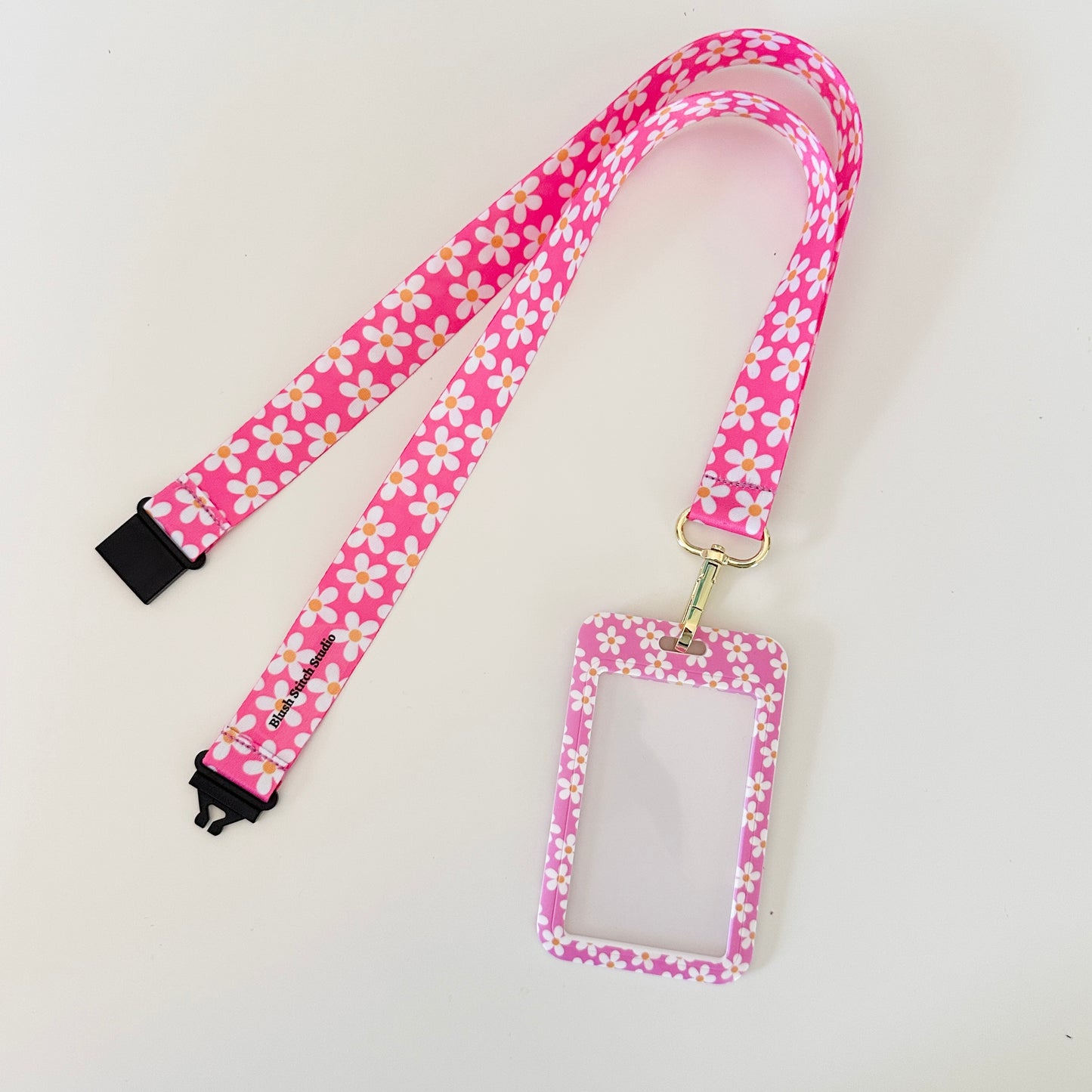 Pink floral lanyard with a matching ID holder on a light gray background
