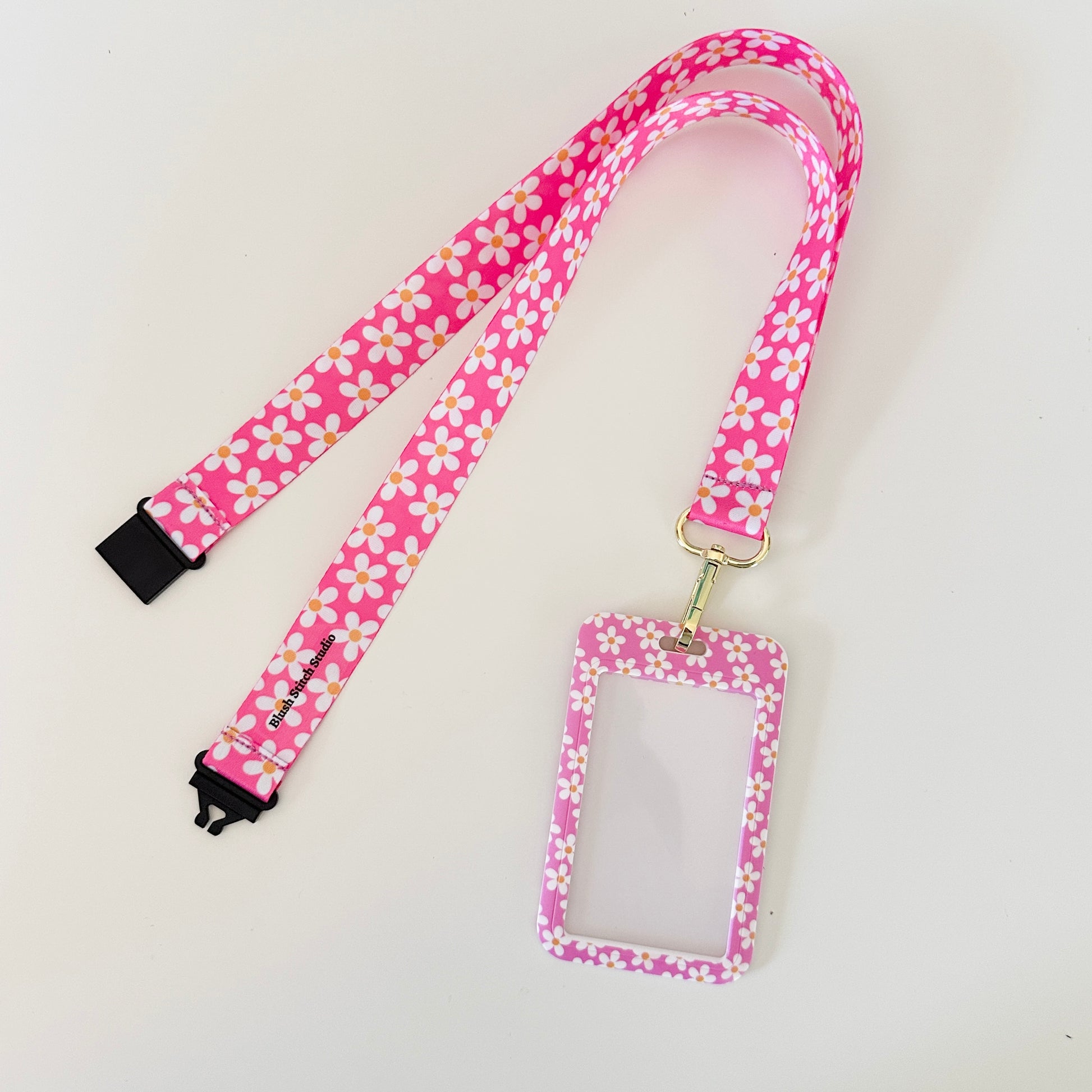 Pink floral lanyard with a matching ID holder on a light gray background