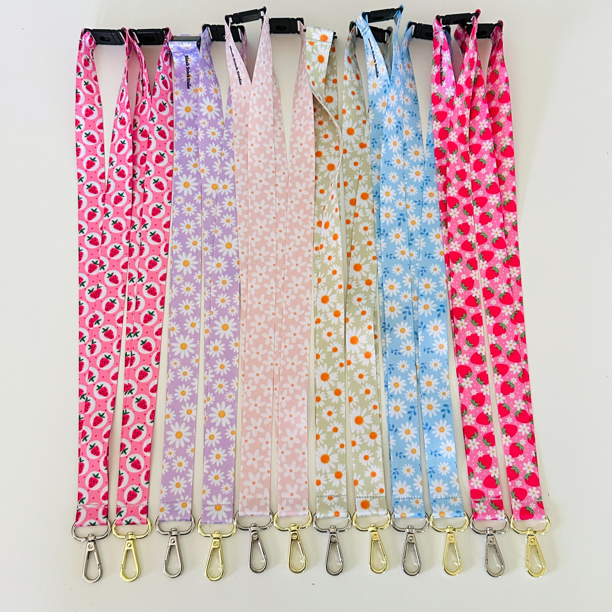Set of colorful patterned lanyards hanging on a rack against a white background