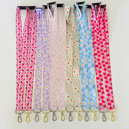 Set of colorful patterned lanyards hanging on a rack against a white background