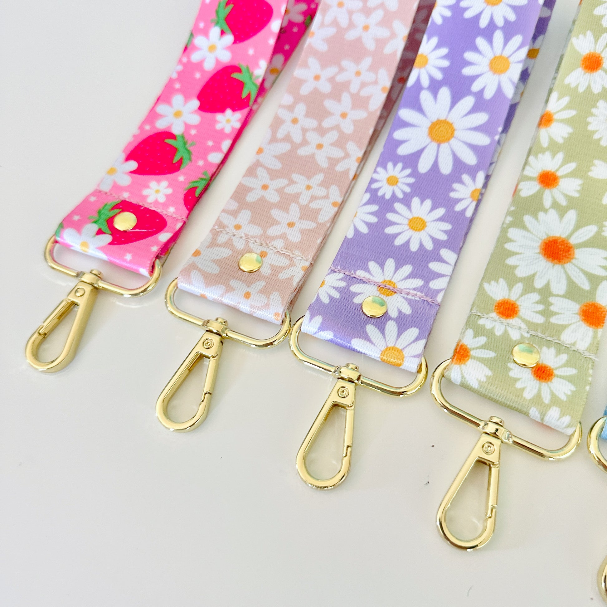 Set of colorful fabric keychains with floral patterns and gold clasp on a white background