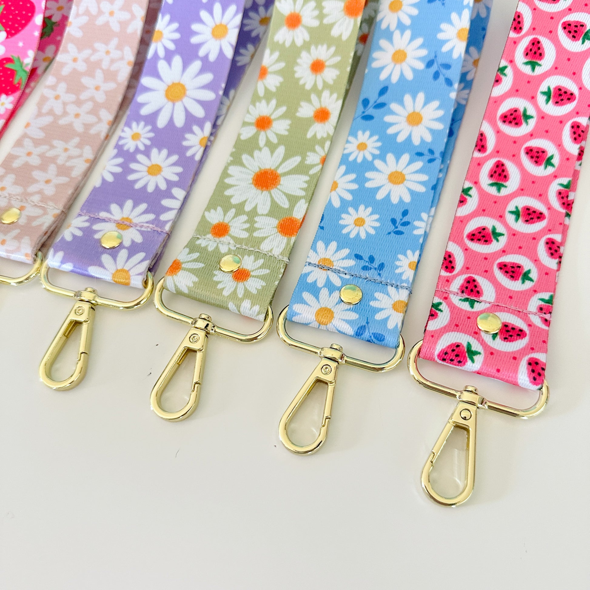 Set of colorful fabric straps with floral and fruit patterns on a light gray background.