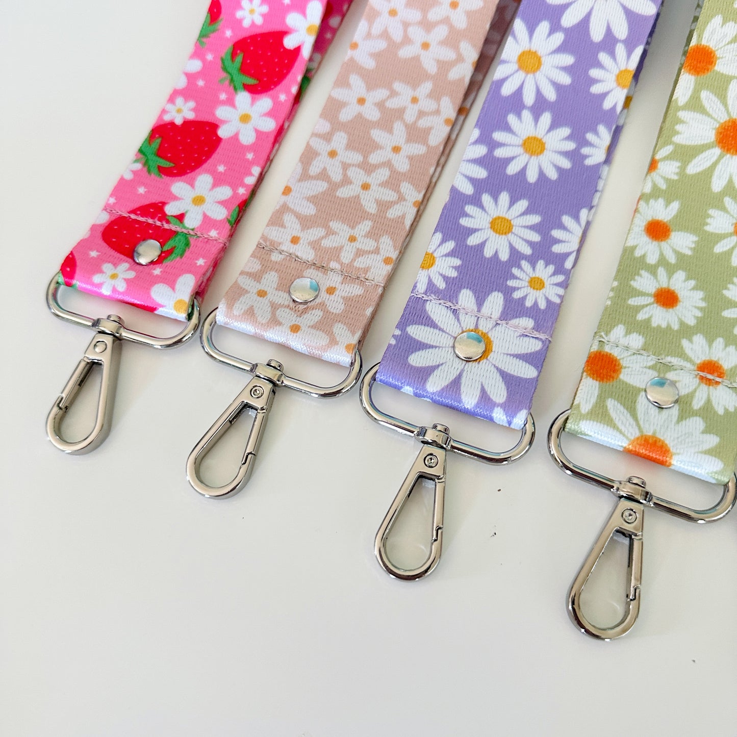 Four fabric keychains with floral patterns on a white background