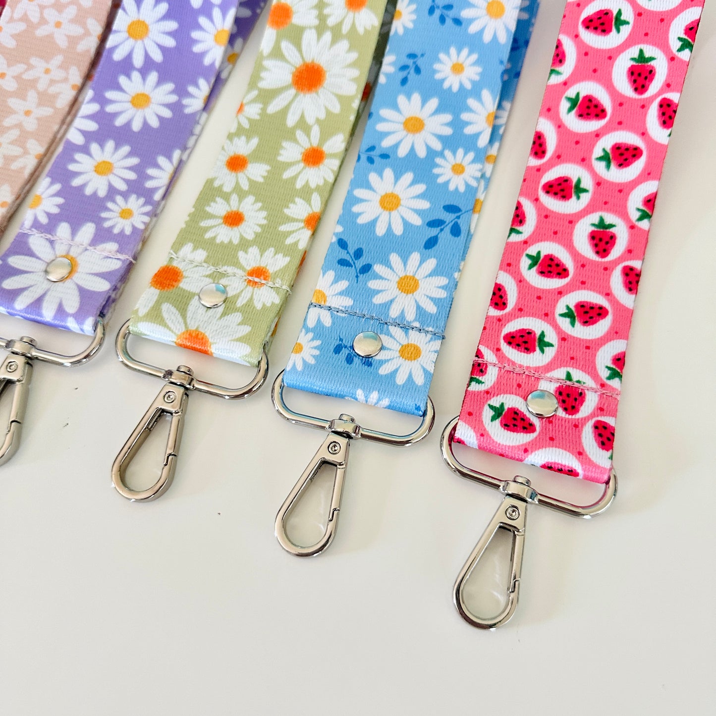 Set of colorful fabric keychains with floral and fruit patterns on a light background