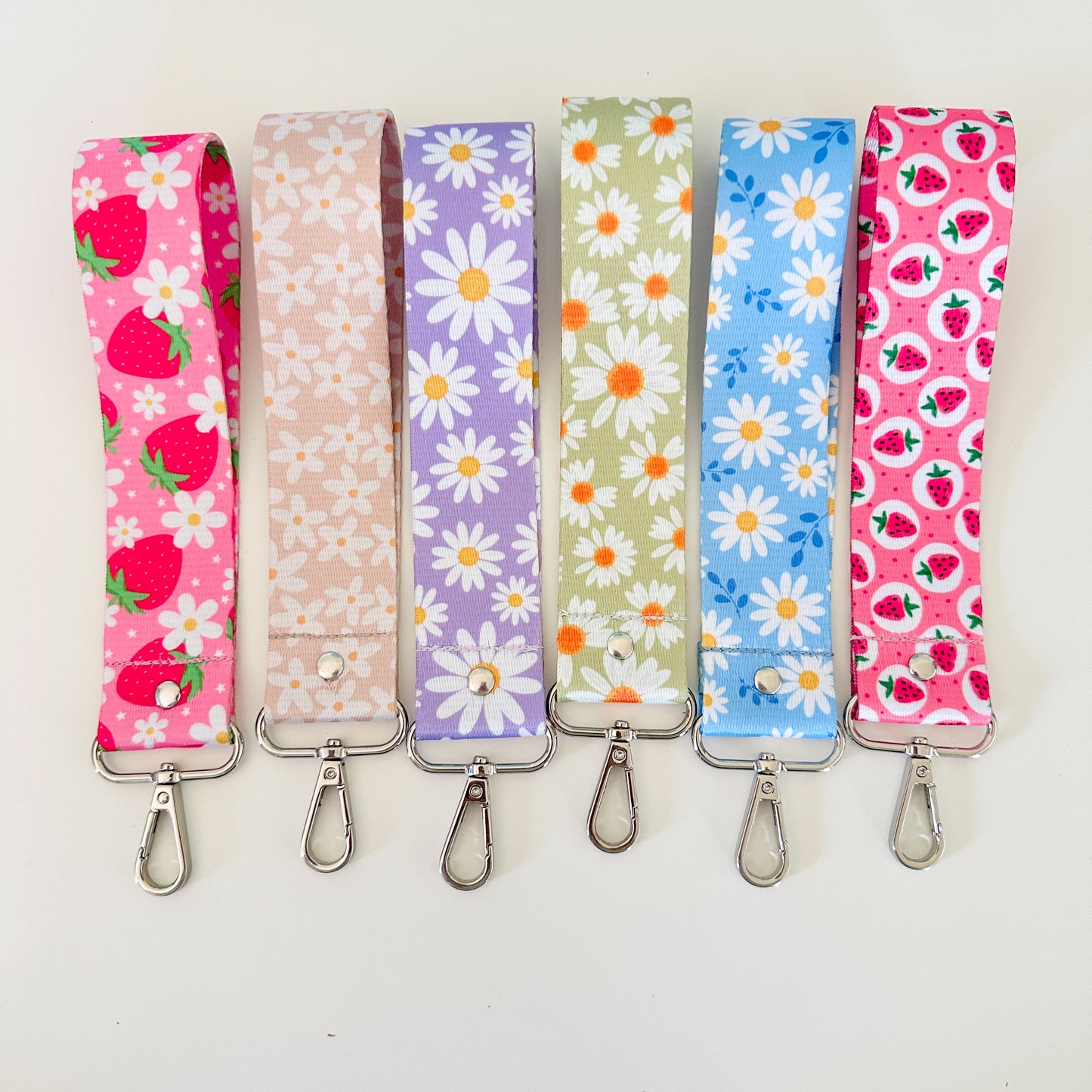 Set of six floral and strawberry patterned lanyards on a white background