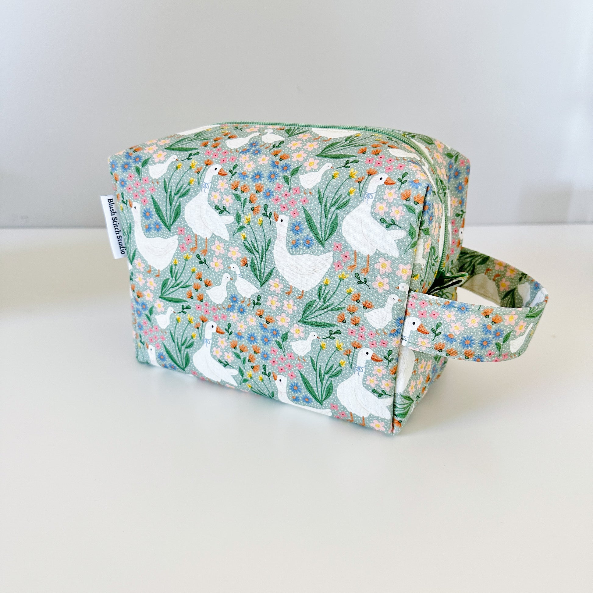 Fabric bag with a green floral and goose pattern on a white background