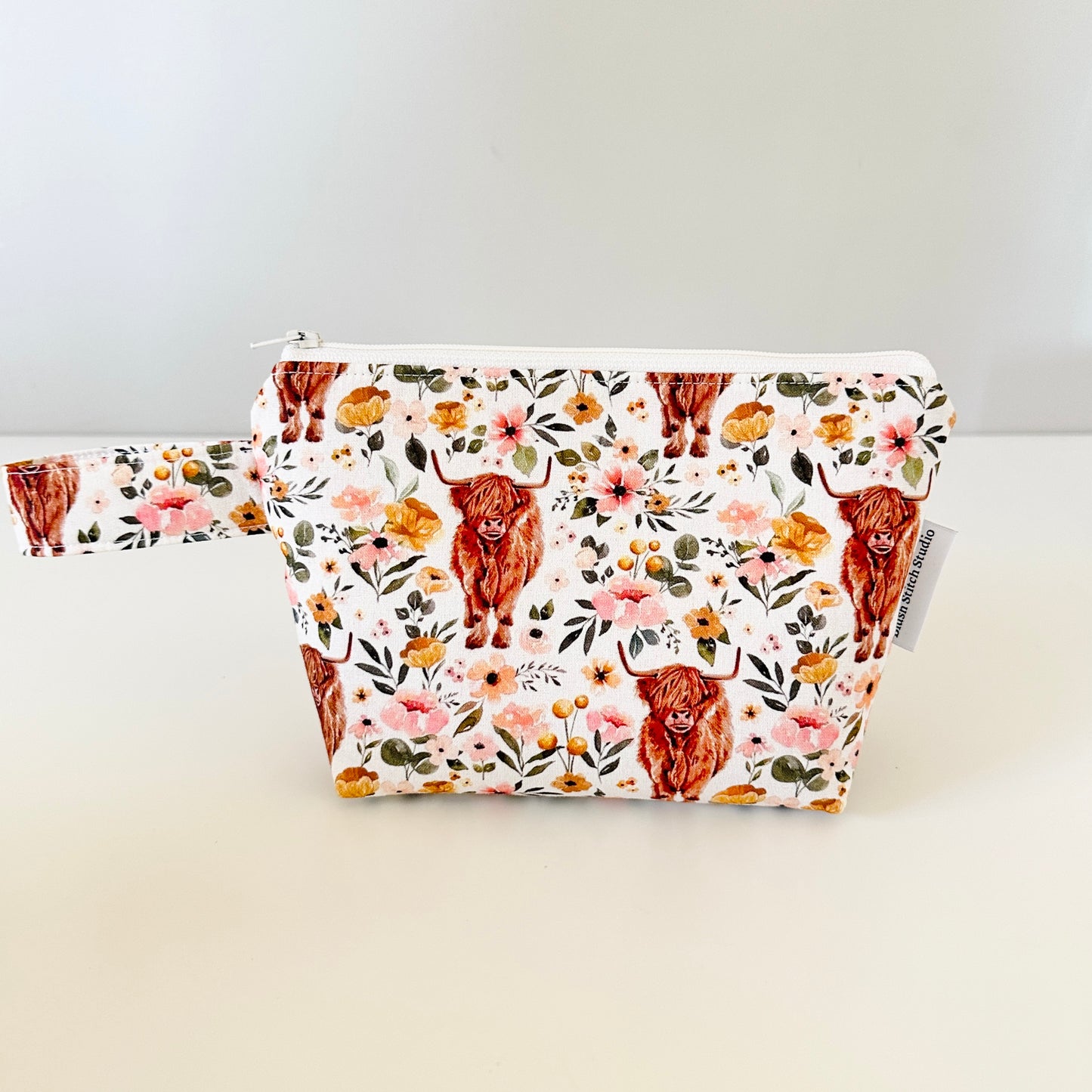 Floral pouch with highland cow design on a white background