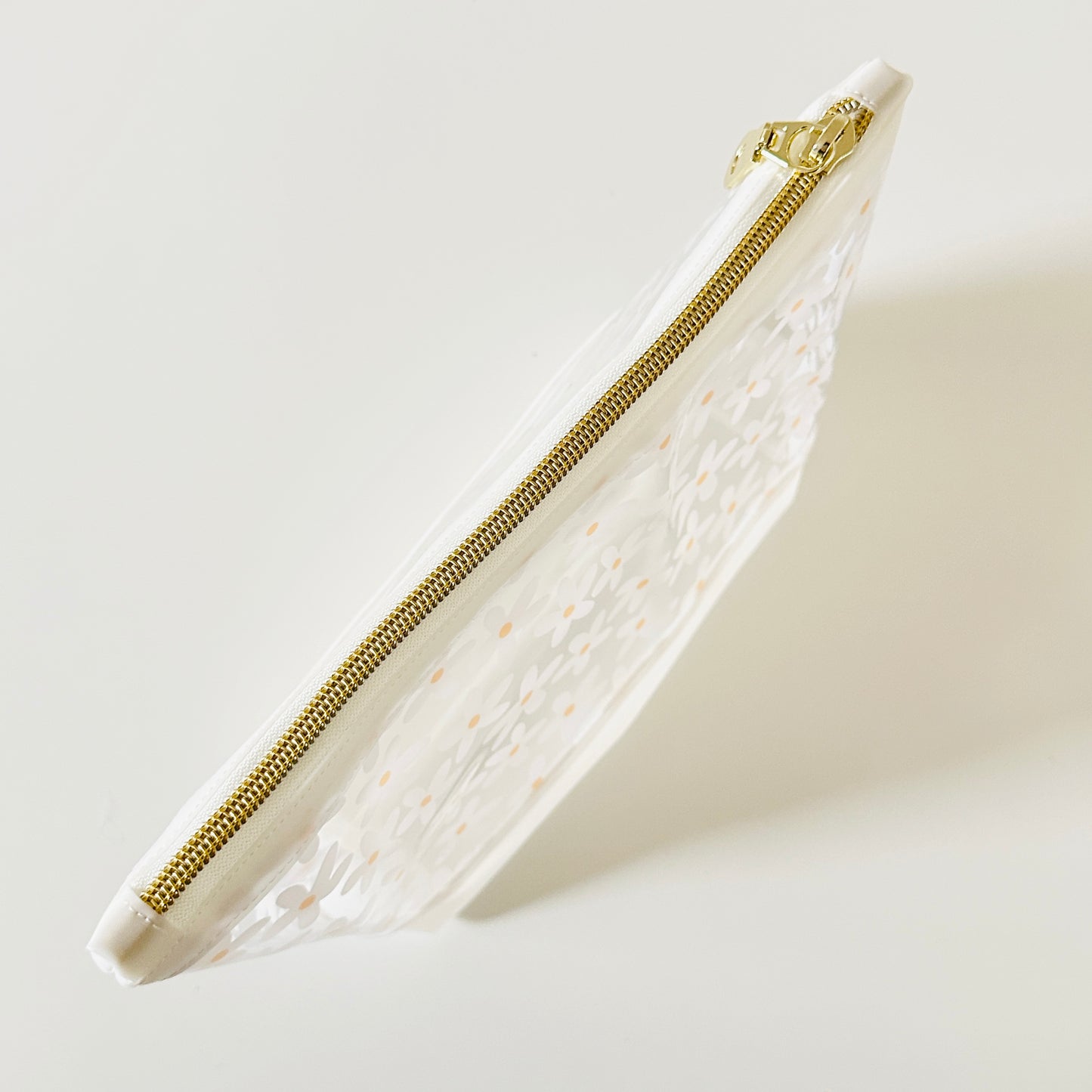 Clear pouch with white floral pattern on a light gray background