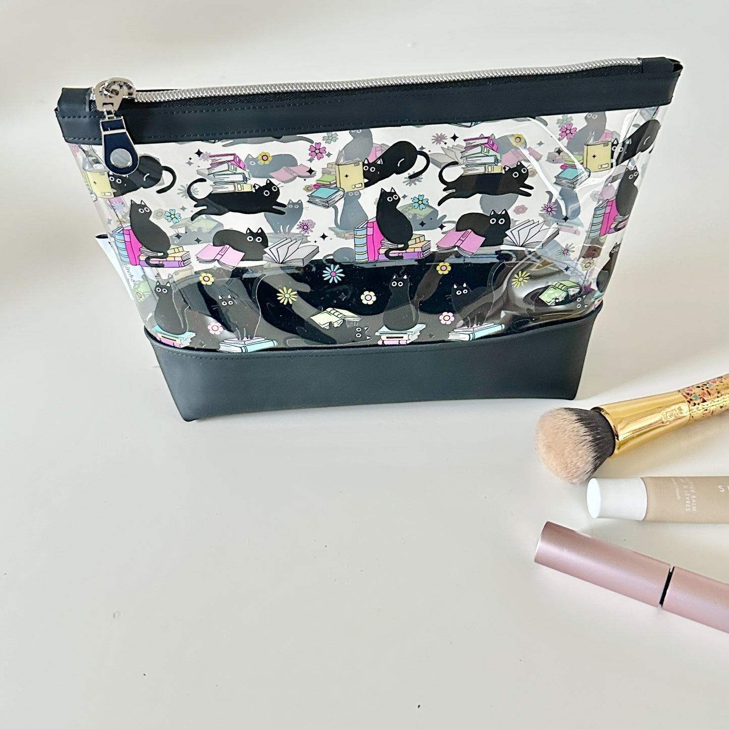clear makeup bag with a black cat and book pattern