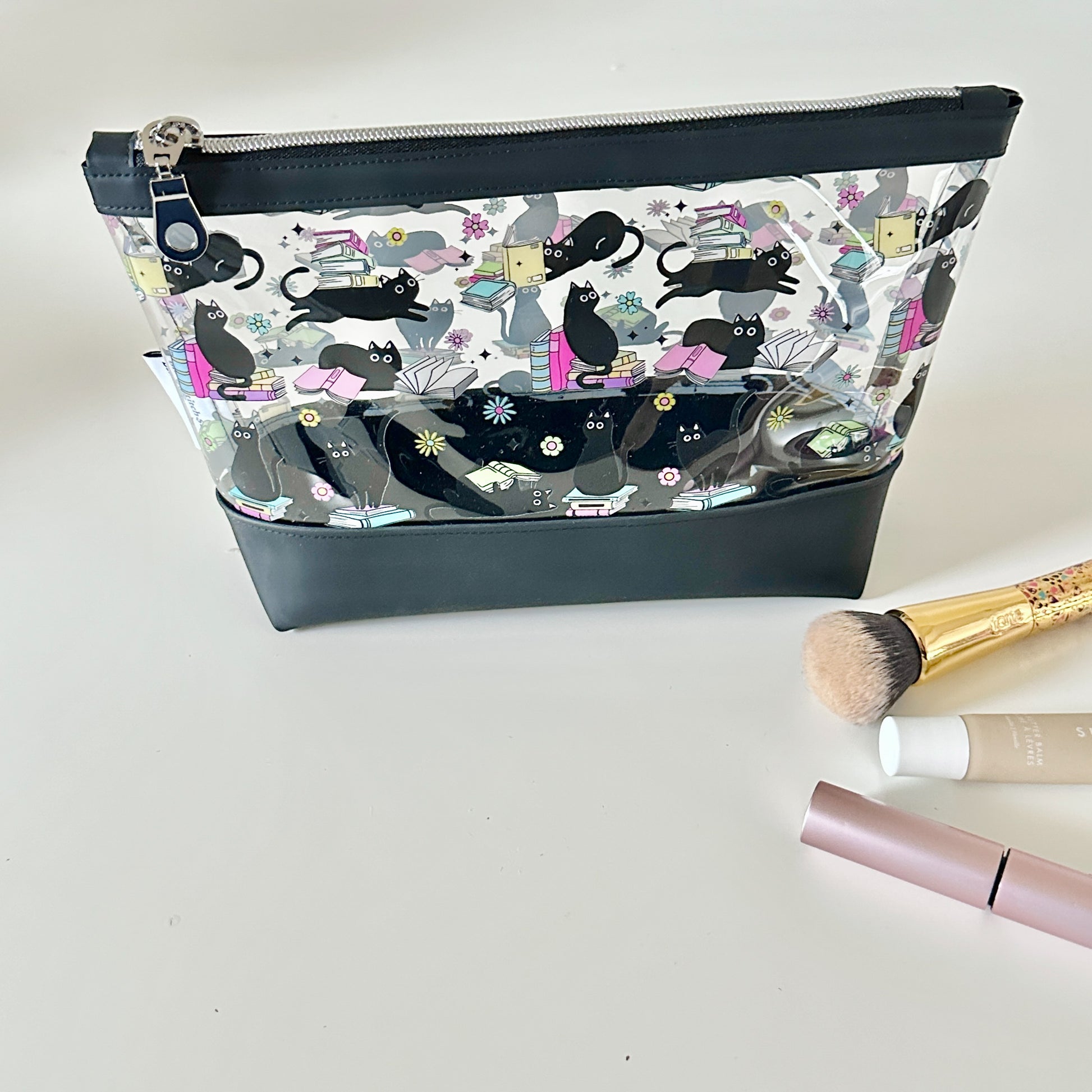 clear makeup bag with a black cat and book pattern