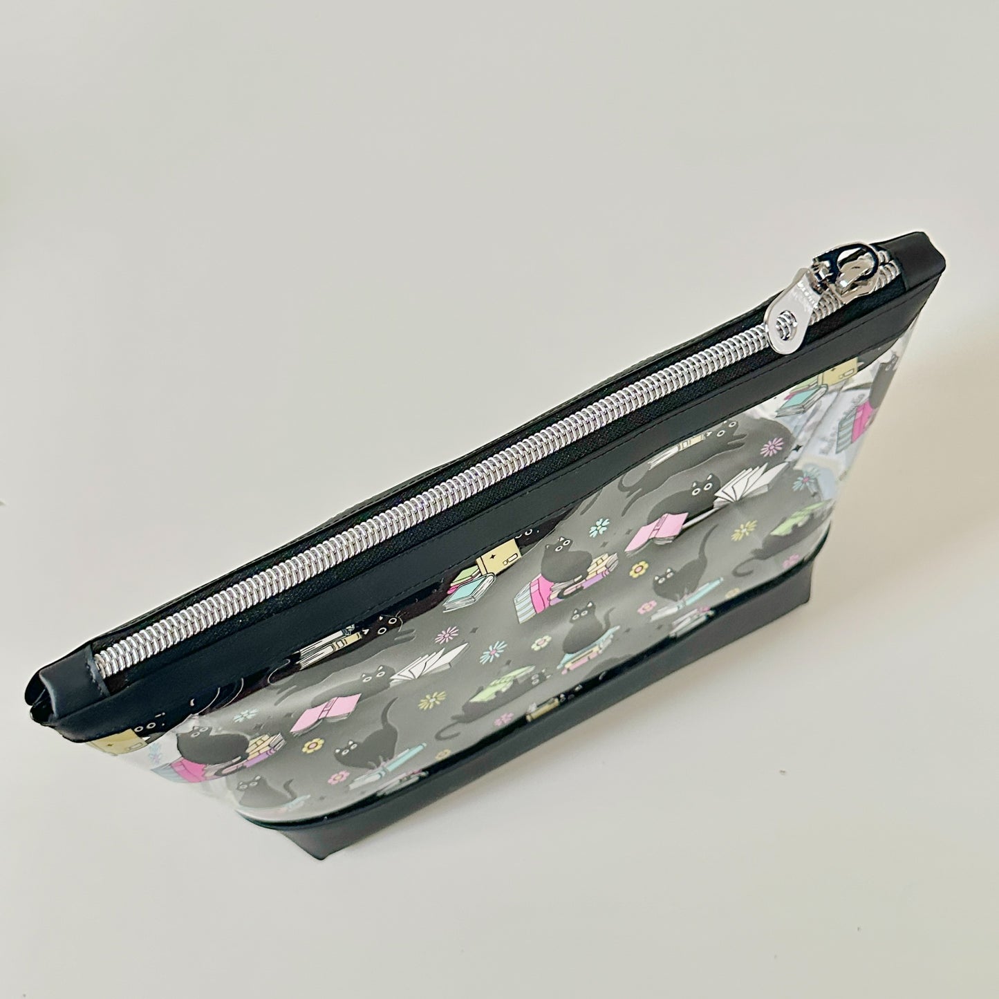 clear makeup bag with a black cat and book pattern