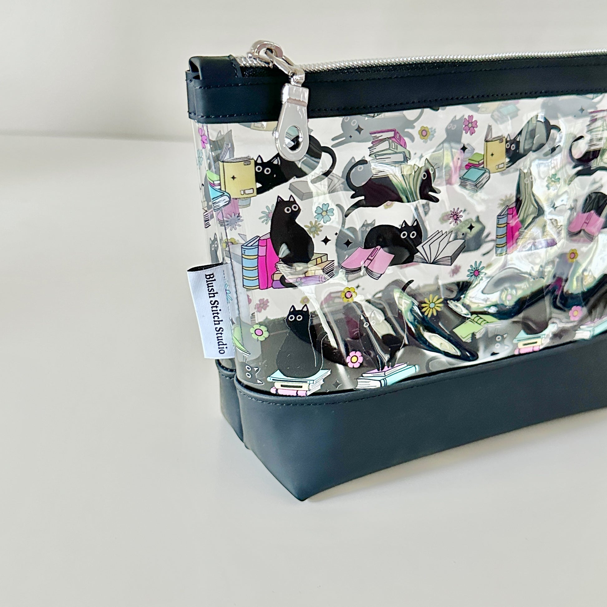 clear makeup bag with a black cat and book pattern