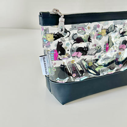 clear makeup bag with a black cat and book pattern