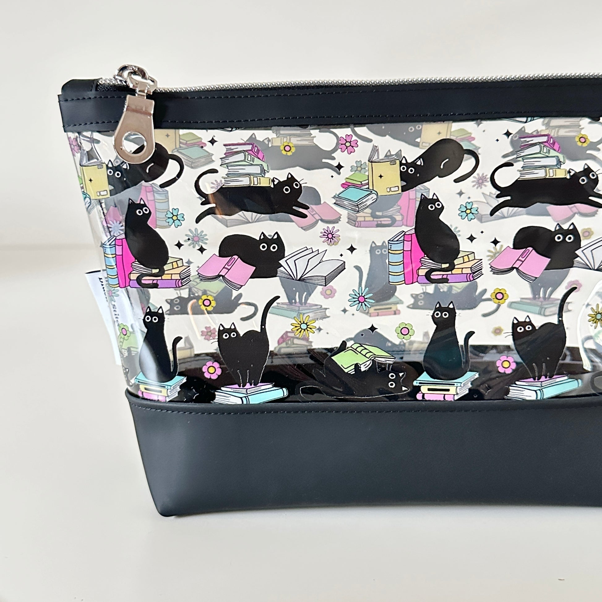 clear makeup bag with a black cat and book pattern