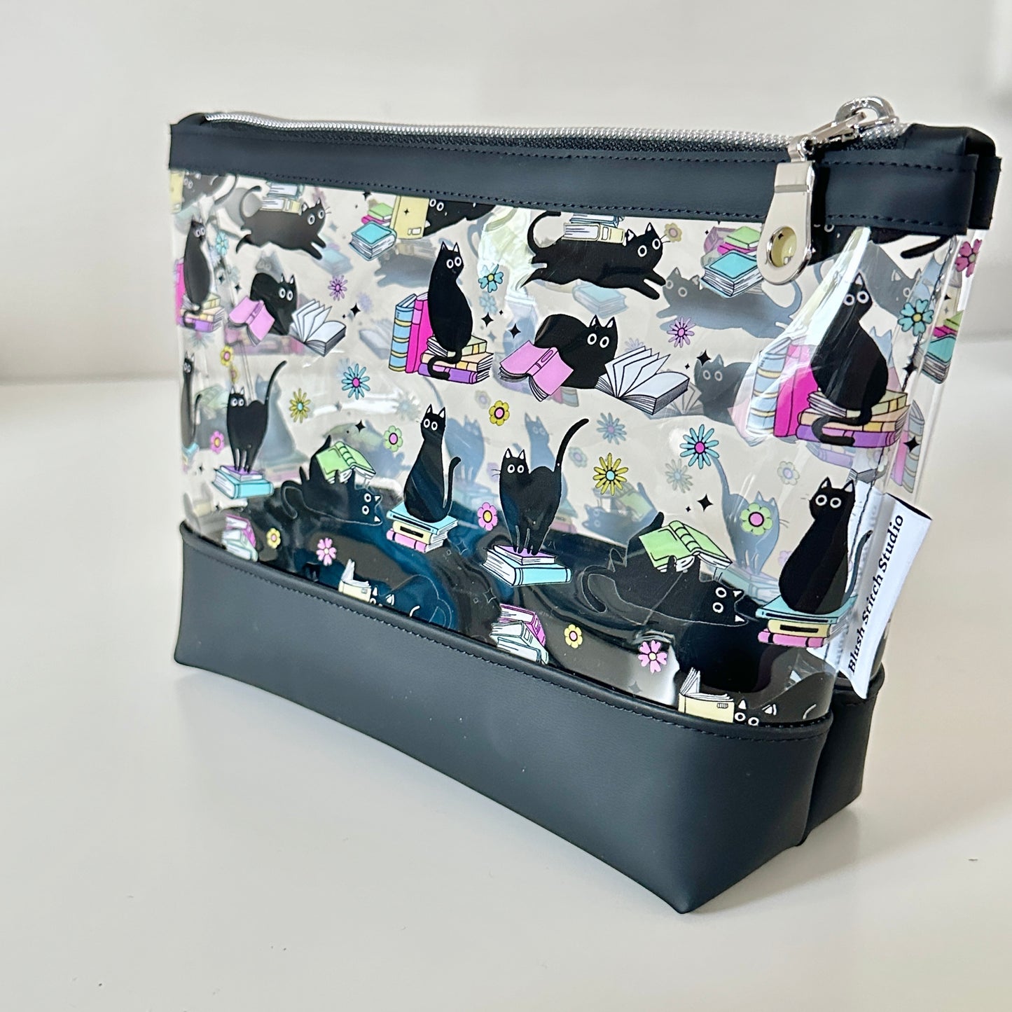 Black cosmetic bag with cat pattern on a light gray background