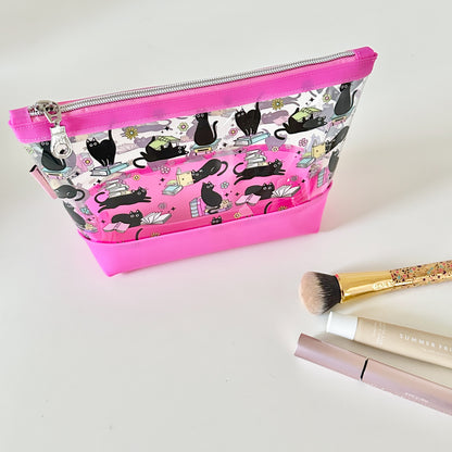Makeup bag with black cat pattern and pink zipper on a white background