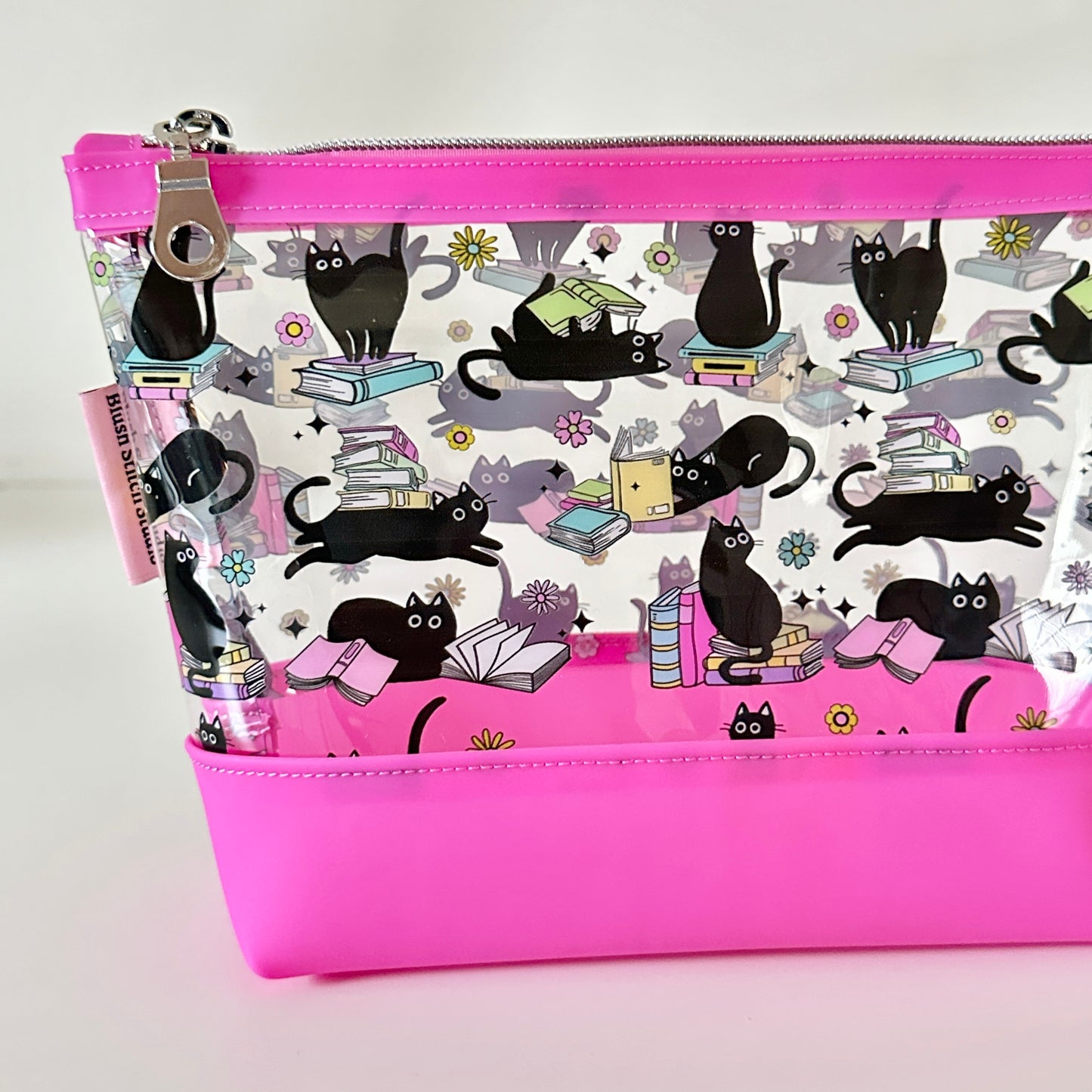 clear makeup bag with a black cat and book pattern pink bottom