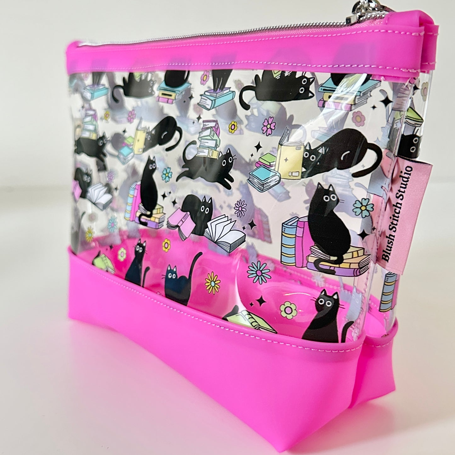 clear makeup bag with a black cat and book pattern pink bottom