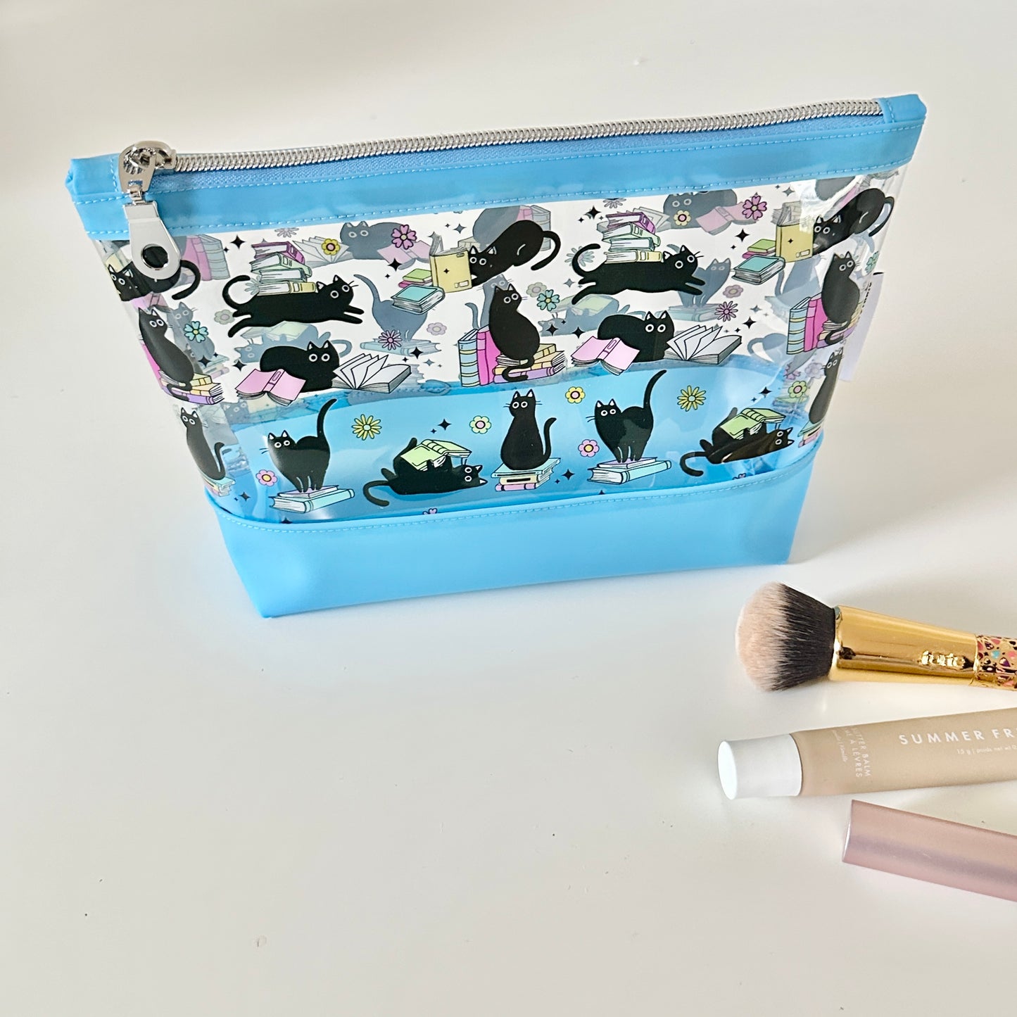 clear makeup bag with a black cat and book pattern blue bottom