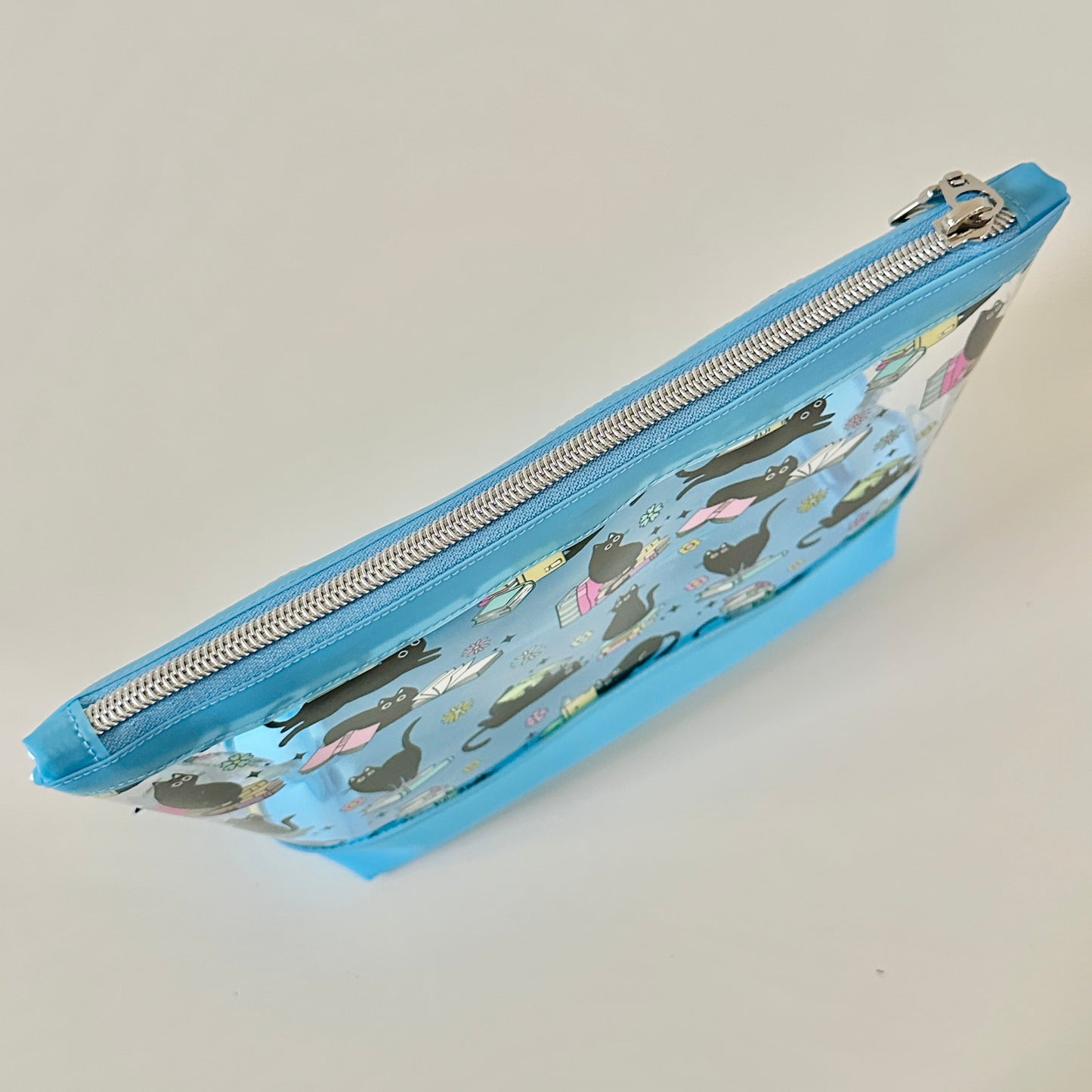 clear makeup bag with a black cat and book pattern blue bottom