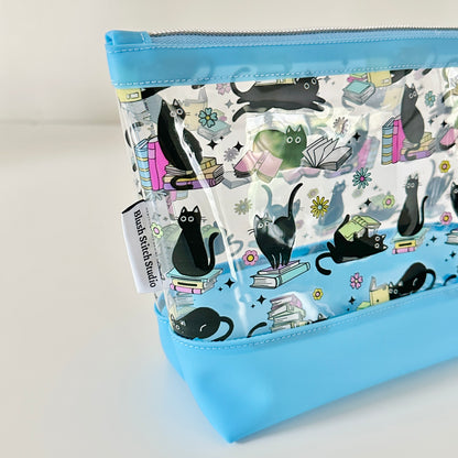 clear makeup bag with a black cat and book pattern blue bottom