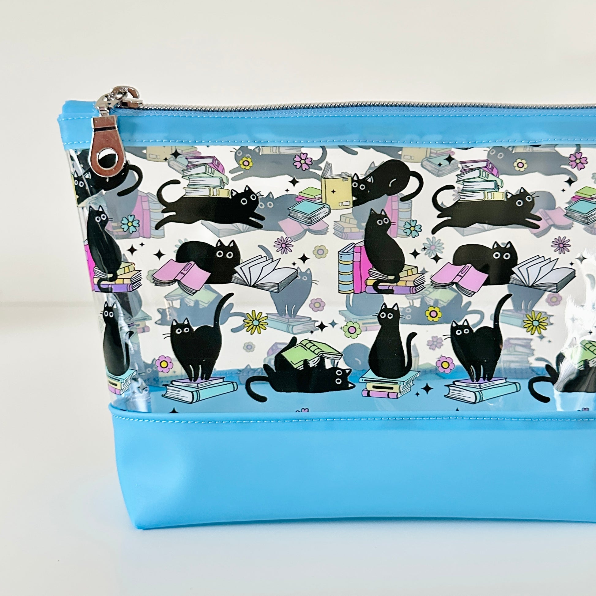 clear makeup bag with a black cat and book pattern blue bottom