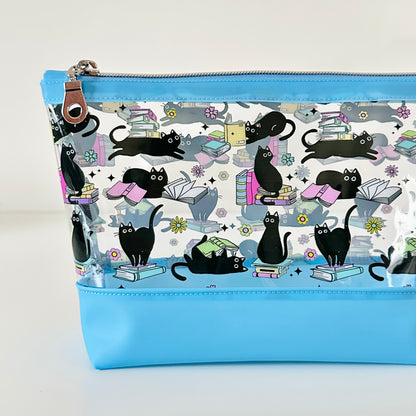 clear makeup bag with a black cat and book pattern blue bottom