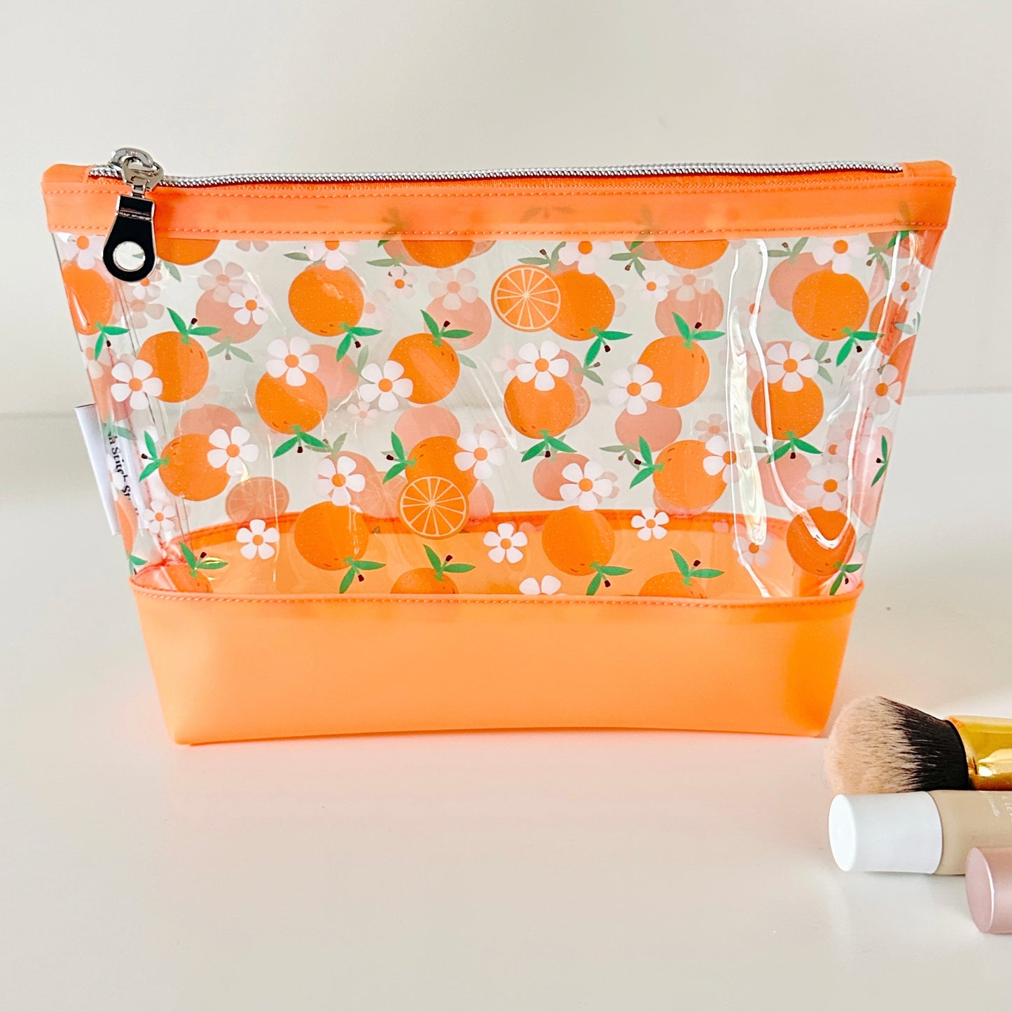 Clear makeup bag with an orange pattern on a light background