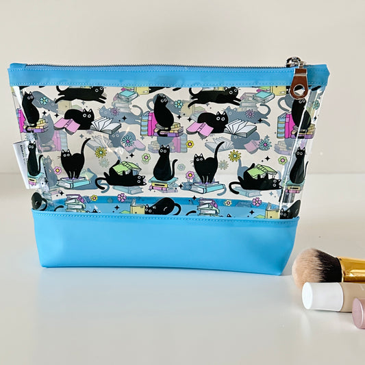 Cosmetic bag with black cat pattern and blue zipper on a white background