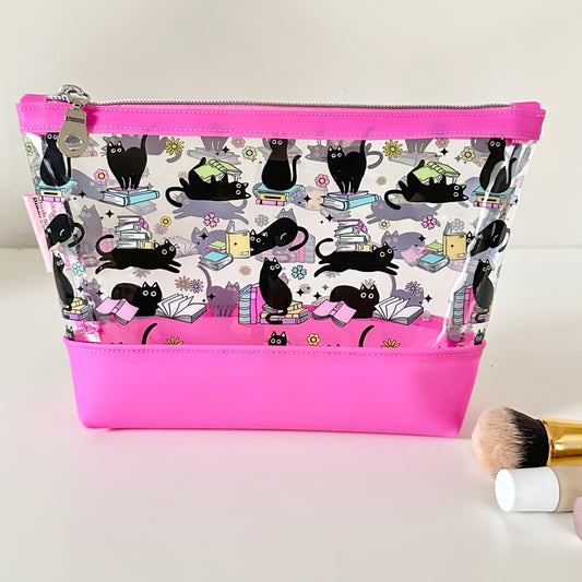 clear makeup bag with a black cat and book pattern pink bottom
