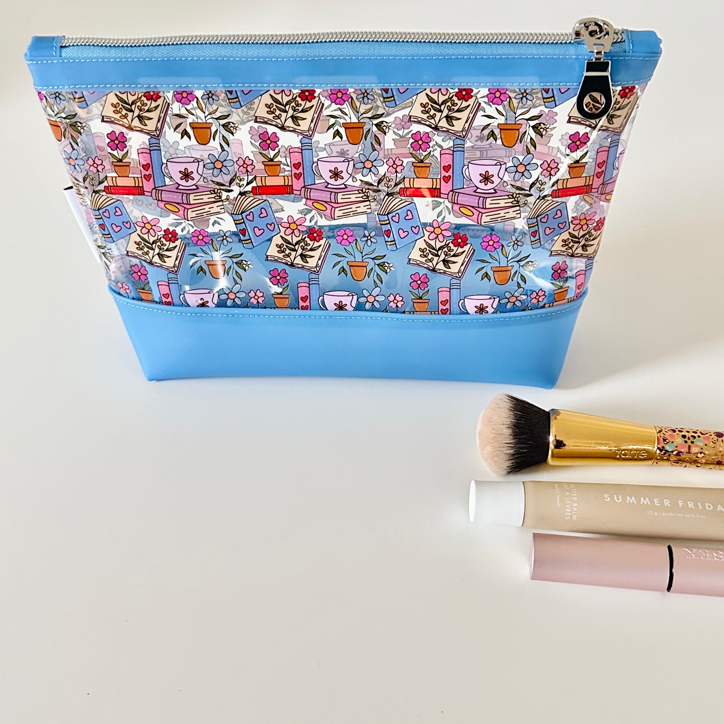 Cosmetic bag with floral and book design on a white background