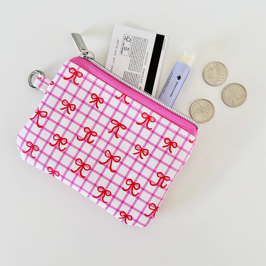Pink checkered coquette vegan leather coin purse with red bows on a white background