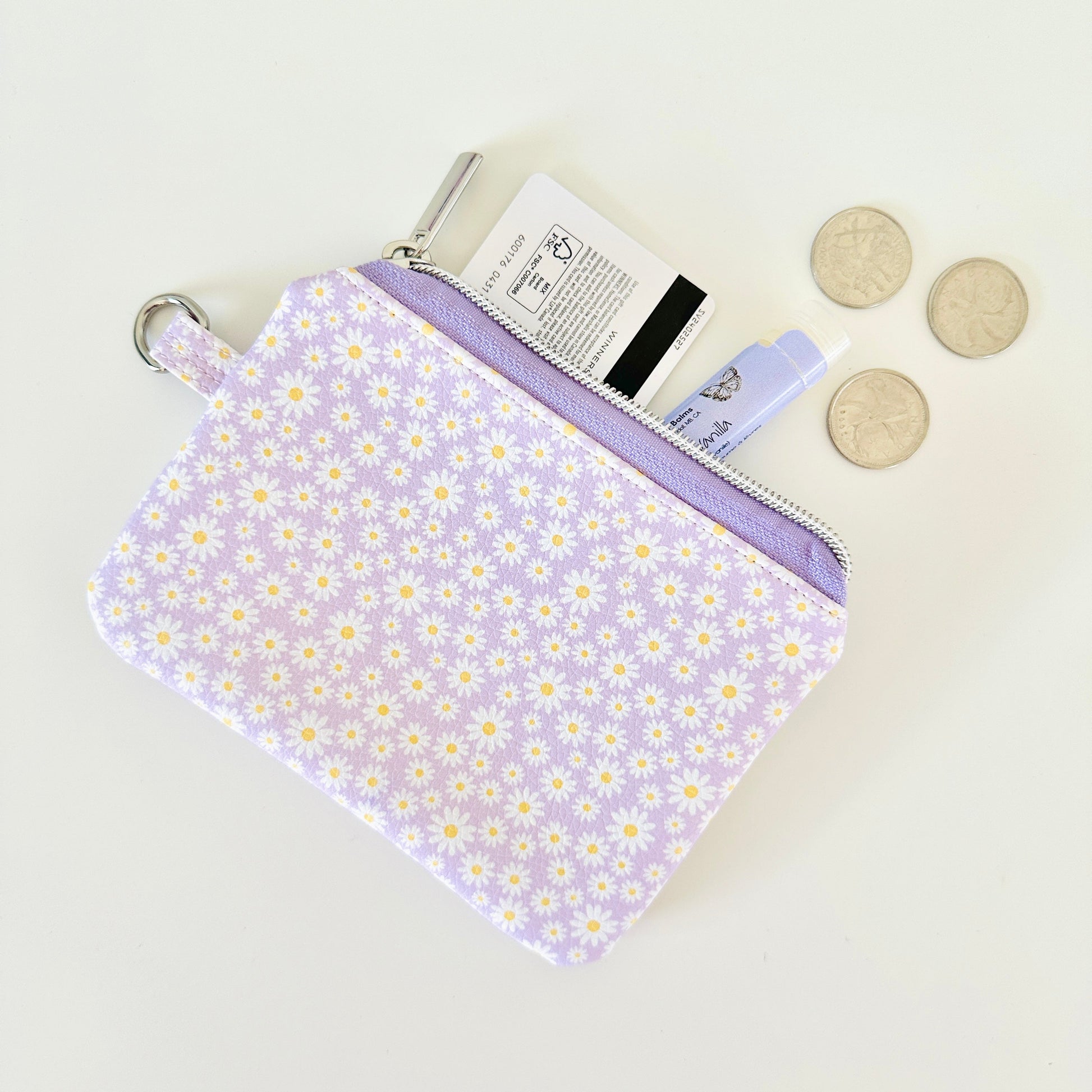 Purple floral-patterned coin purse with coins on a light gray background