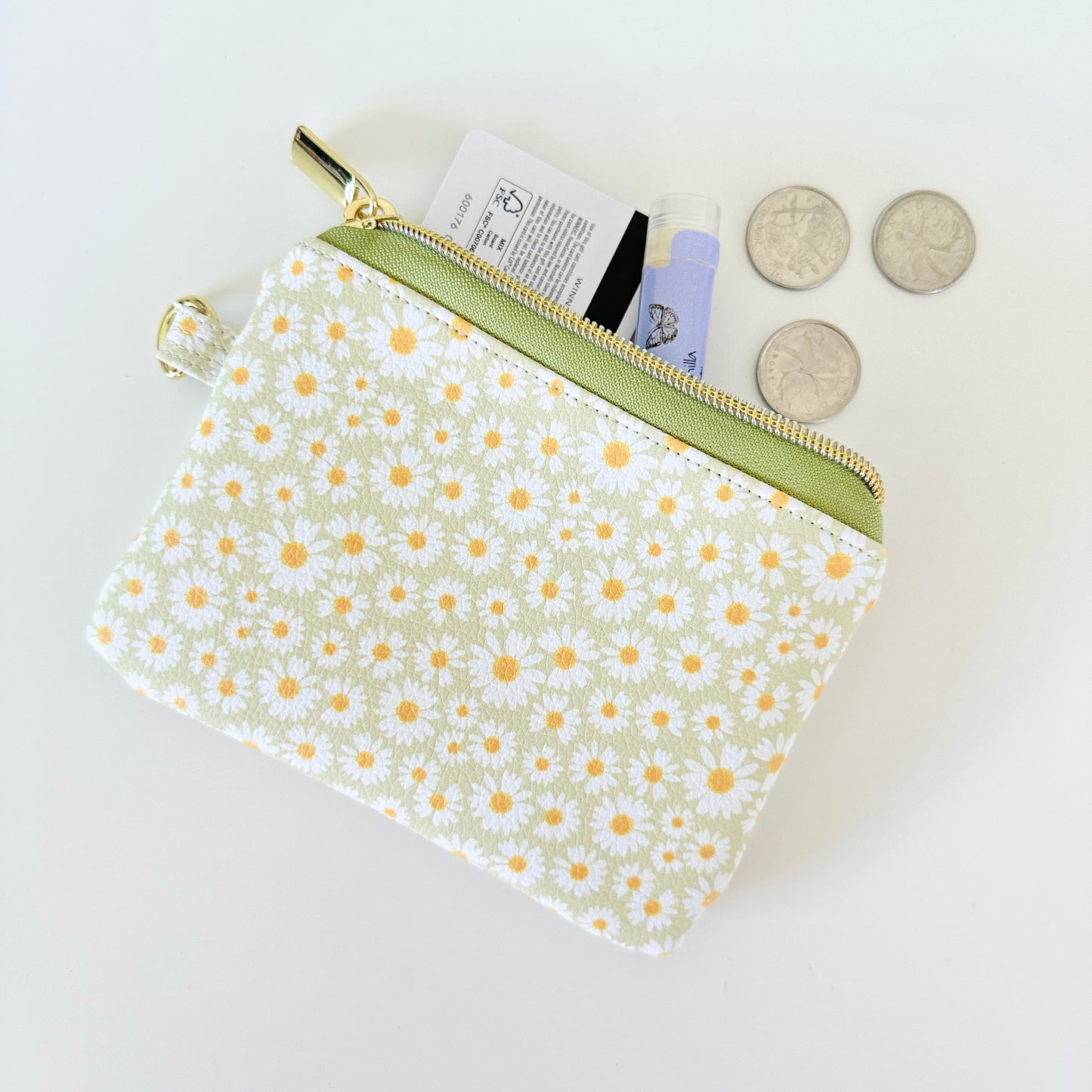 green daisy Floral-patterned coin purse  with coins and cards on a light background