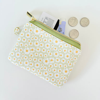 green daisy Floral-patterned coin purse  with coins and cards on a light background
