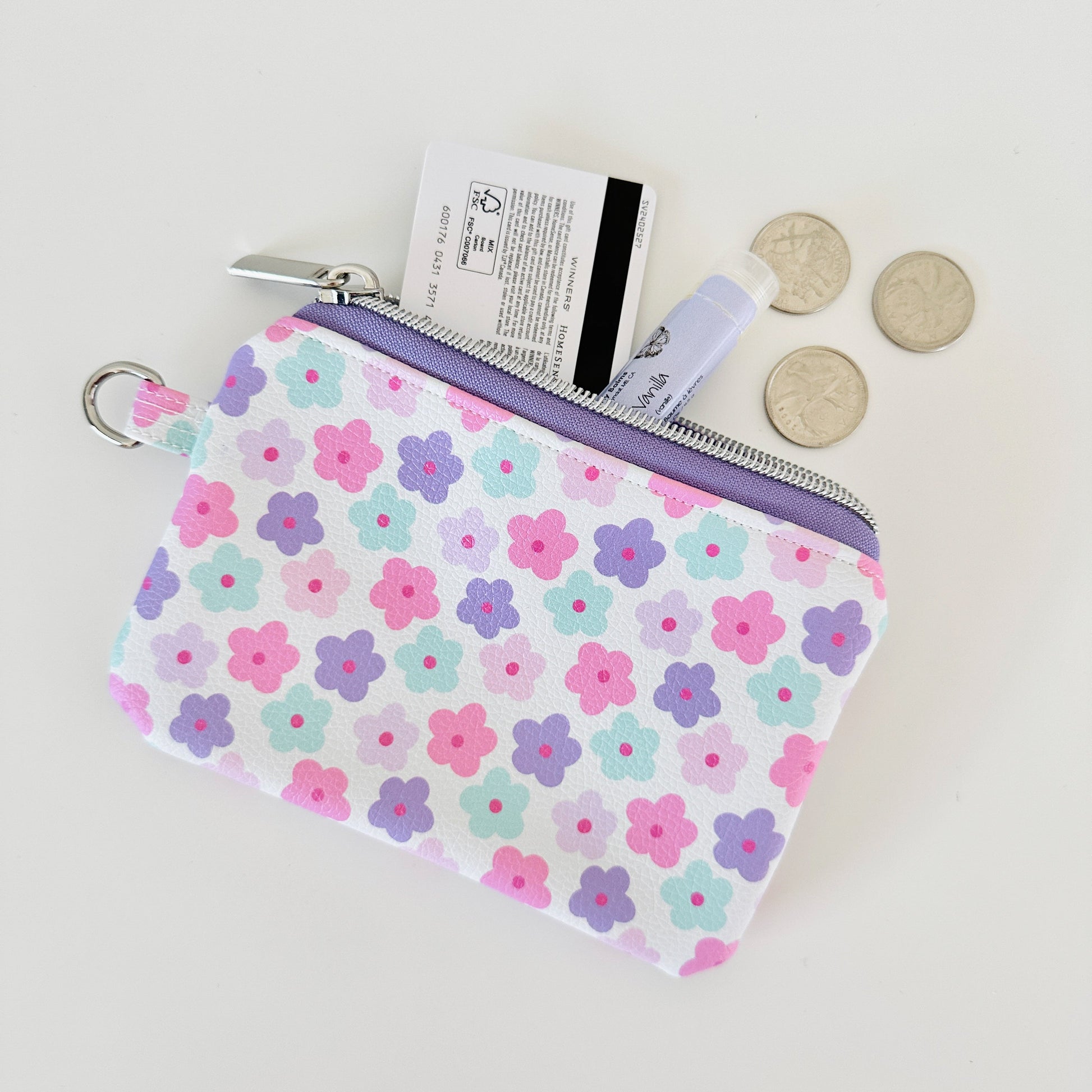 pink and purple Floral-patterned coin purse with coins and cards on a white background