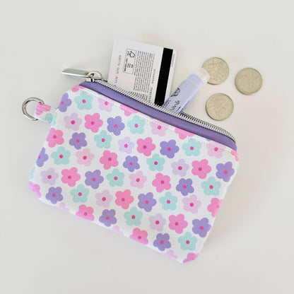pink and purple Floral-patterned coin purse with coins and cards on a white background