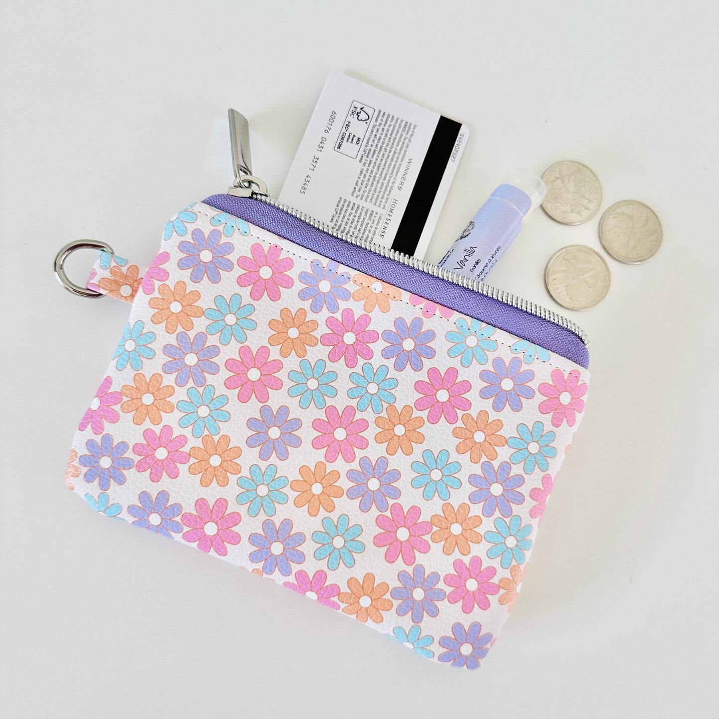 Floral patterned coin purse with cards and coins on a white background