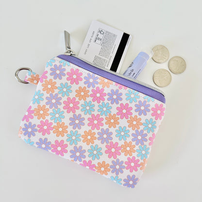 Floral patterned coin purse with cards and coins on a white background