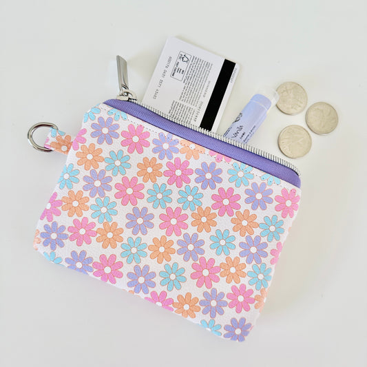 Floral patterned coin purse with cards and coins on a white background